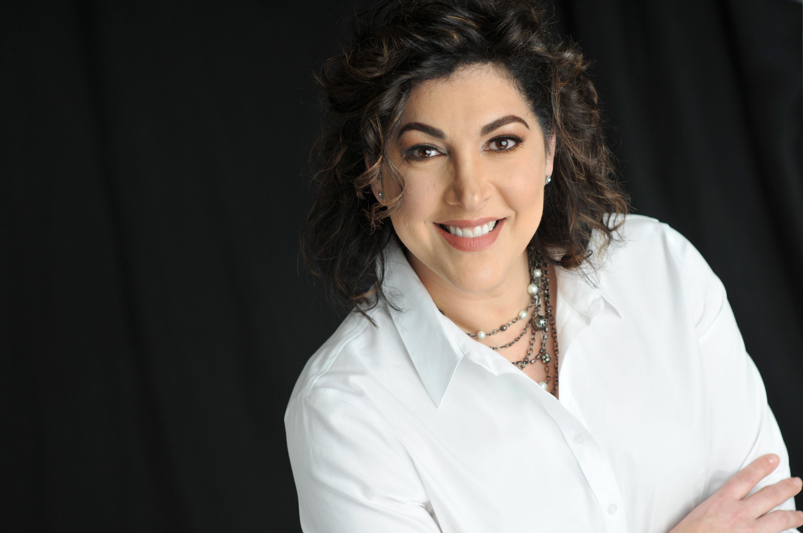 Photo of Jamie Valvano wearing a white shirt on a black background